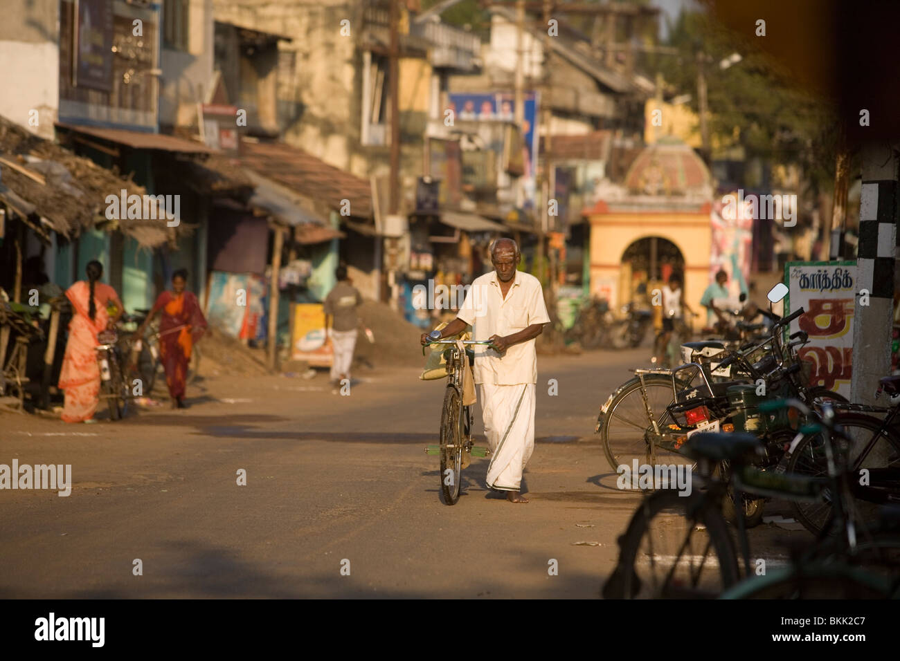Ein Mann schiebt sein Fahrrad eine Straße hinunter in die Tempelstadt Swamimalai, Tamil Nadu, Indien Stockfoto