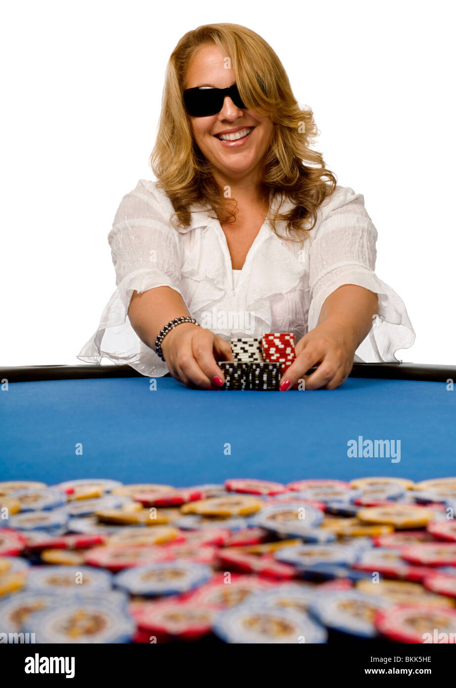 Attraktive blonde Frau schiebt Pokerchips in Richtung Topf auf blauem Filz Tisch. Stockfoto