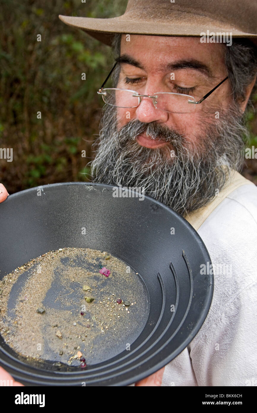 Mann schaut eng Goldmine Pfanne mit Edelsteinen während der Demonstration von Goldwaschen Techniken der 1800er Stockfoto