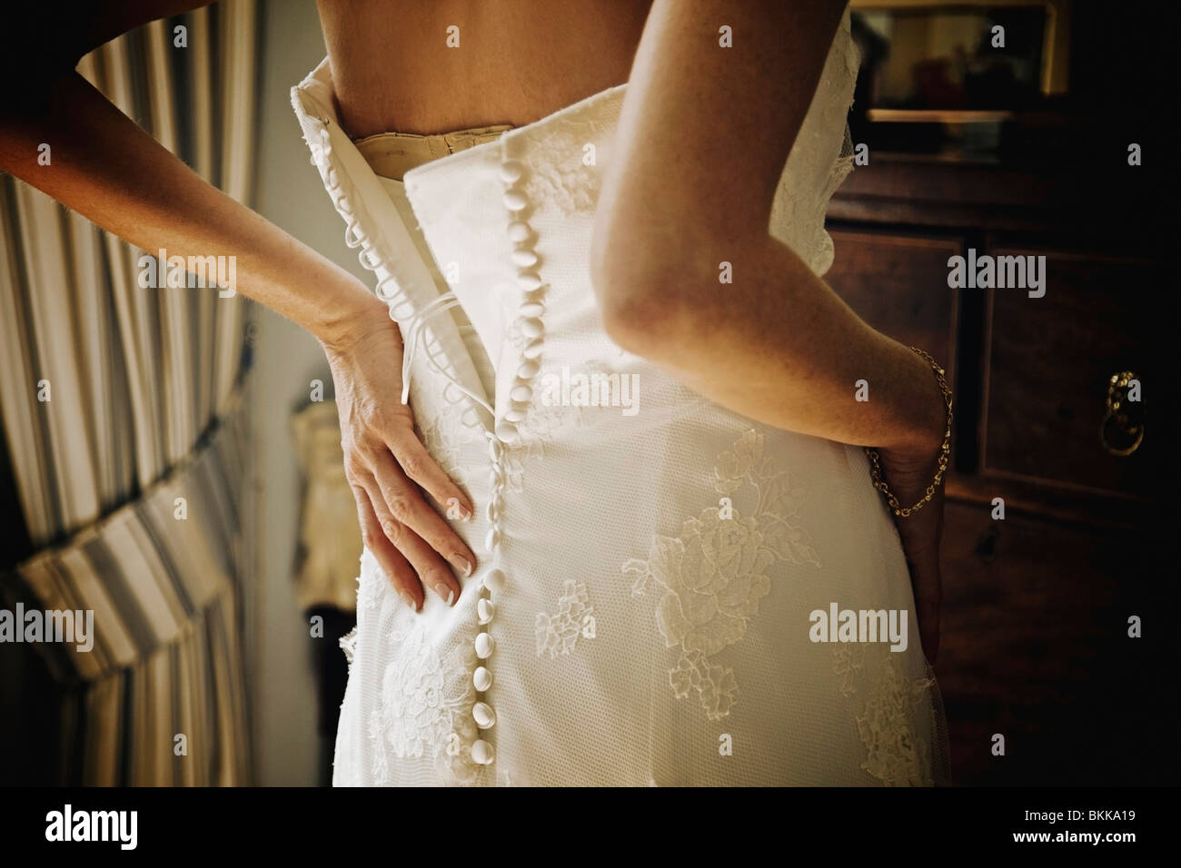 Eine Frau, die Befestigung der Rückseite ihr Hochzeitskleid Stockfoto