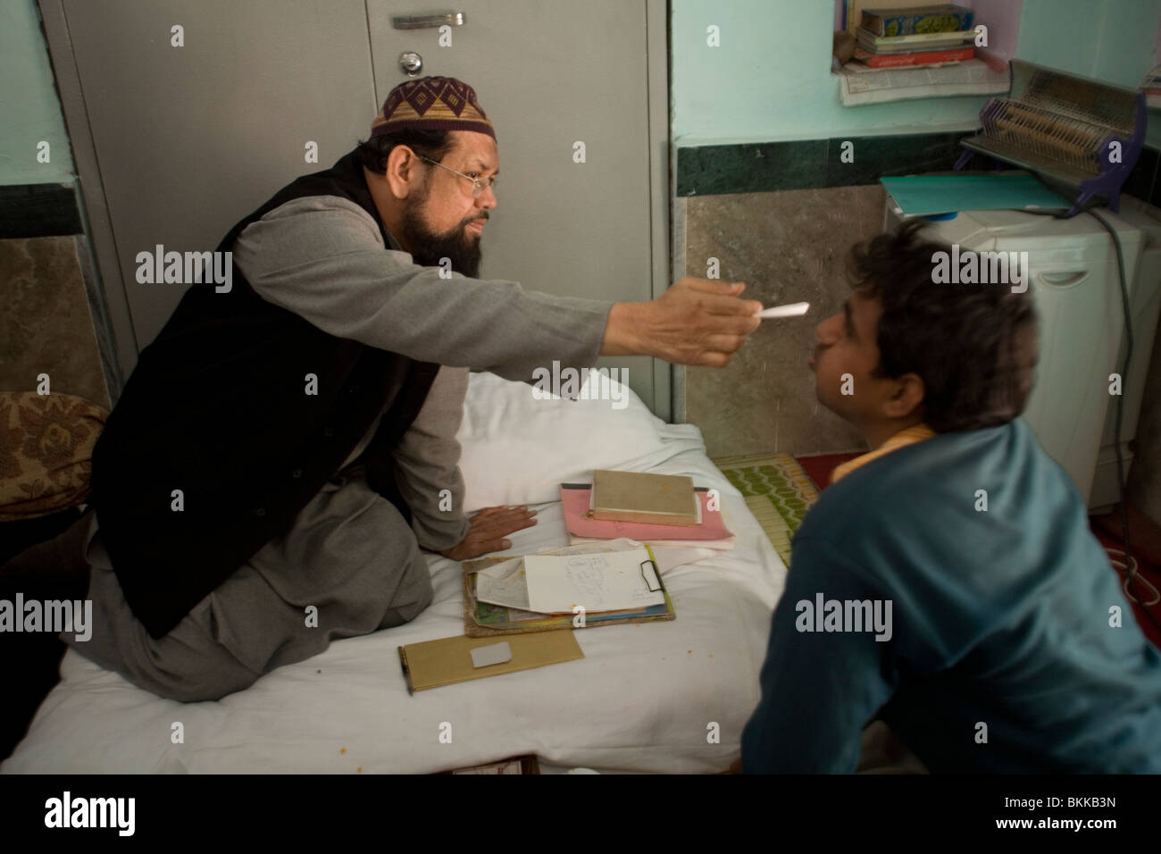 Ein psychisch kranker Mann erträgt einen Exorzismus durch Mohammed Omar Faridi, ein Pir bei Shareef Dargah in Neu-Delhi, Indien Stockfoto