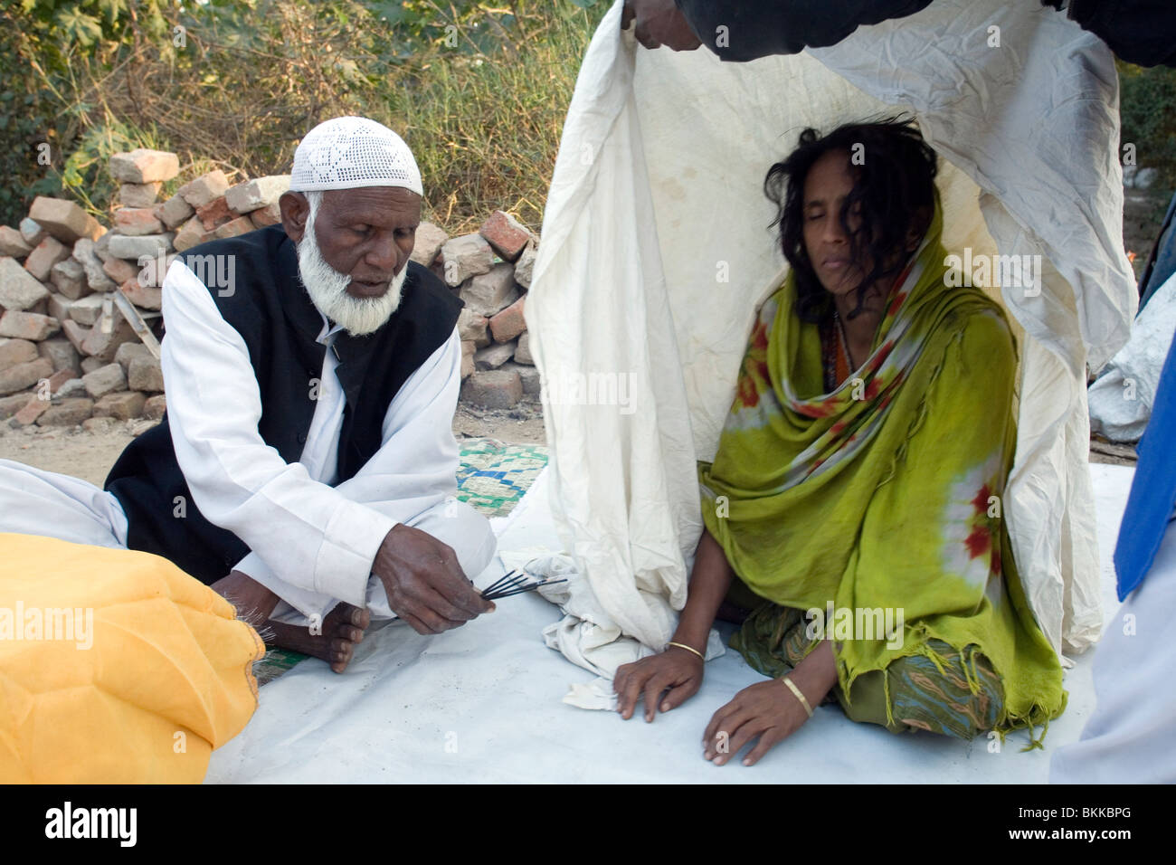 Ein Sufi-Heiligen Mann oder Pir, exorzierte einen Geist von einer Frau in einem Dargah oder Schrein in Süd-Delhi, Indien Stockfoto