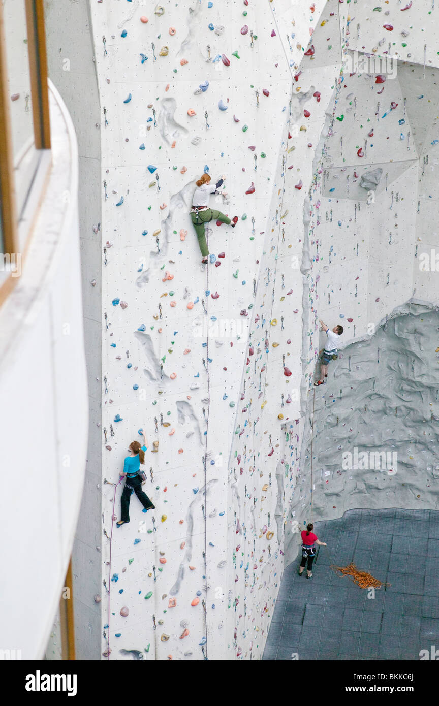 Kletterer aufsteigend eine indoor-Kletterwand mit einer Person vor Ort sichern. Stockfoto