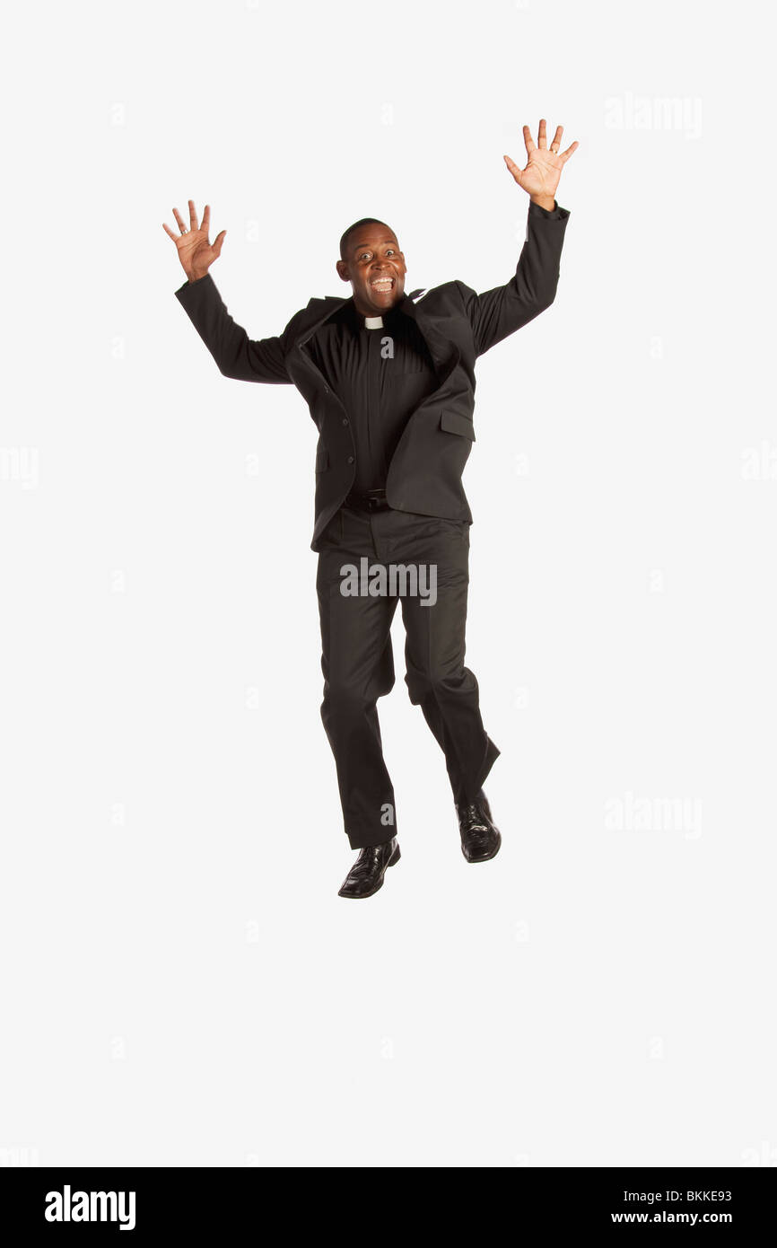 Ein Mann trägt eine klerikal-Kragen und In die Luft springen Stockfoto