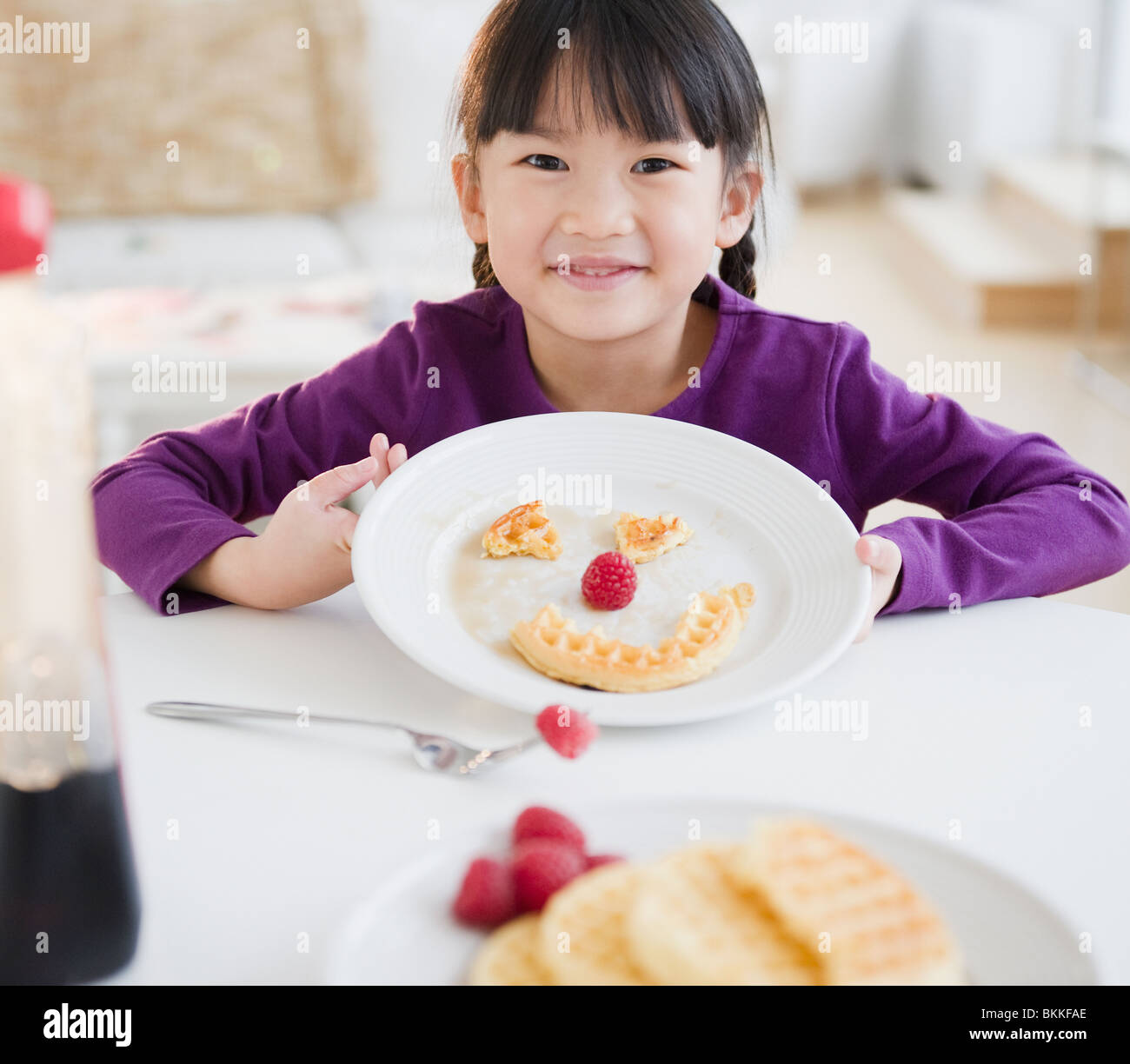 Chinesisches Mädchen Grimasse auf Teller mit Waffel Stockfoto