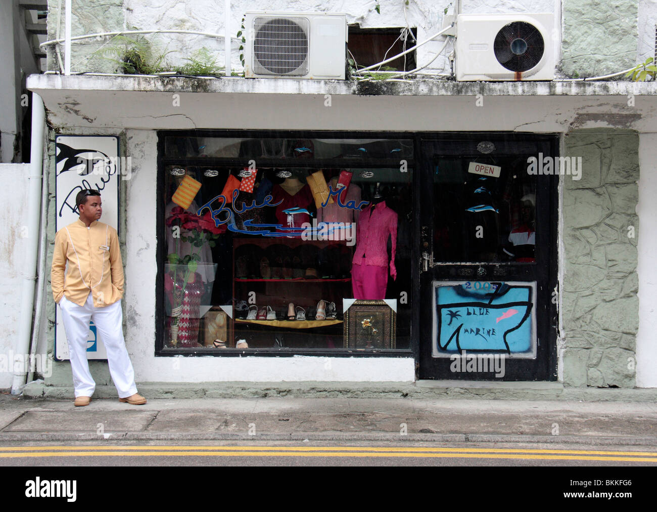 junger Mann tragen modische Kleidung stehen vor einem Kleidungsstück Shop, Victoria, Mahé, Seychellen Stockfoto