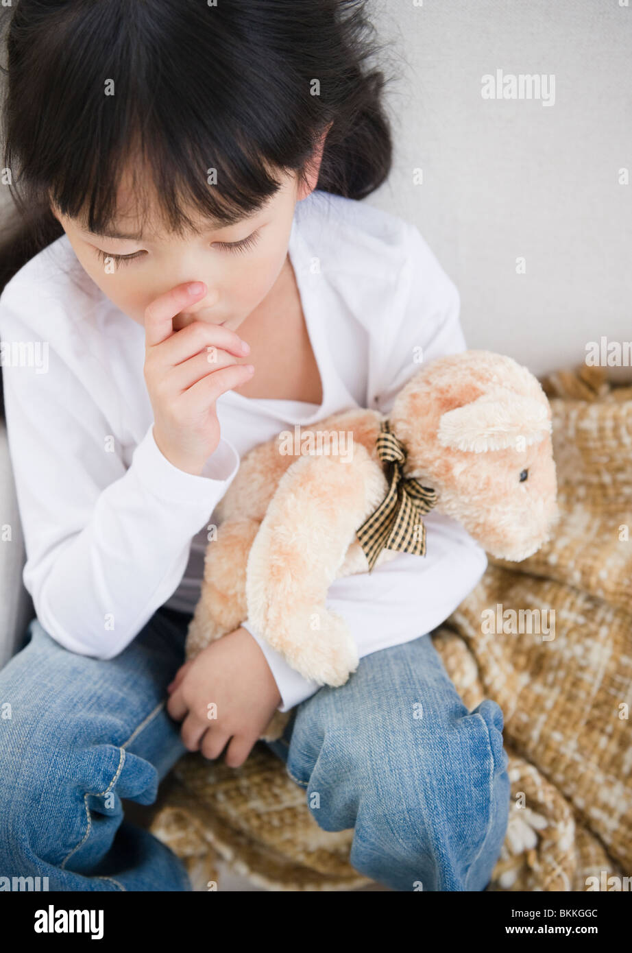 Chinesisches Mädchen Daumenlutschen und halten Teddybär Stockfoto
