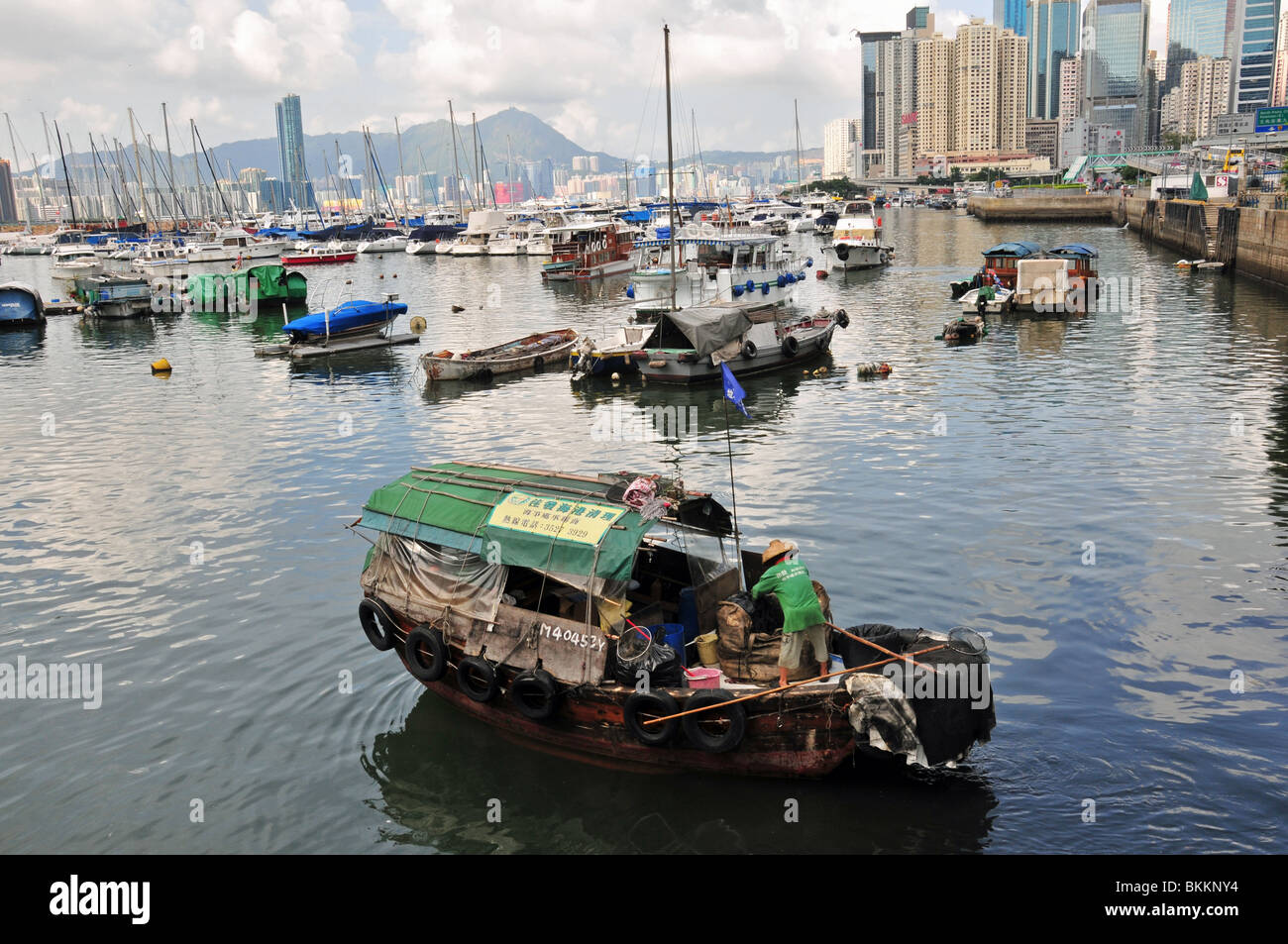 Mann, einen Strohhut tragen auf der Vorderseite ein Sampan-Hausboot in den Gewässern der Causeway Bay Typhoon Shelter, Hong Kong Stockfoto