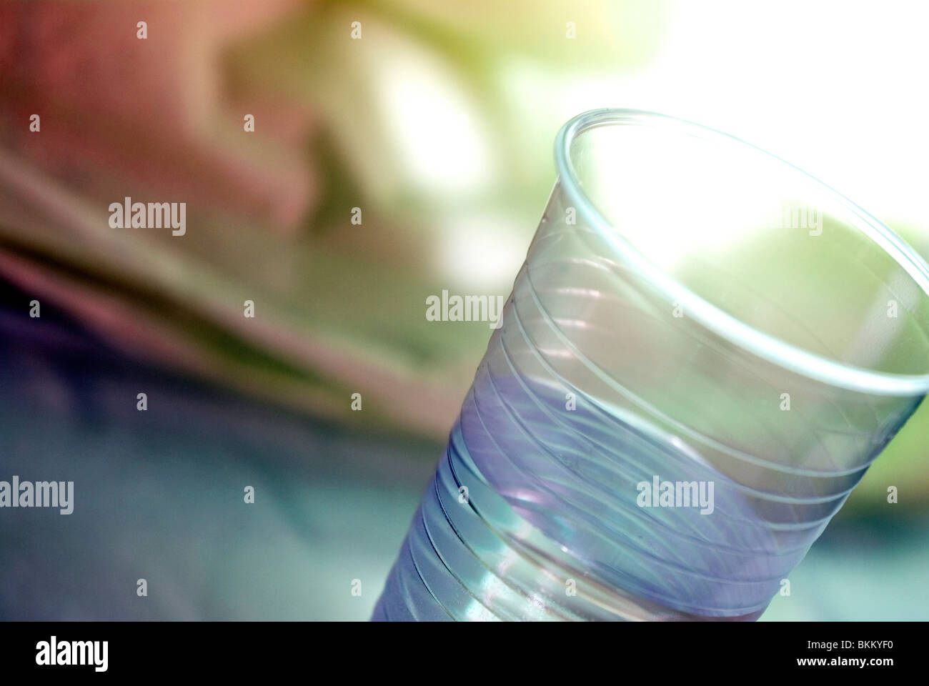 ein Plastikbecher von Wasser vor einem abstrakten Hintergrund Stockfoto