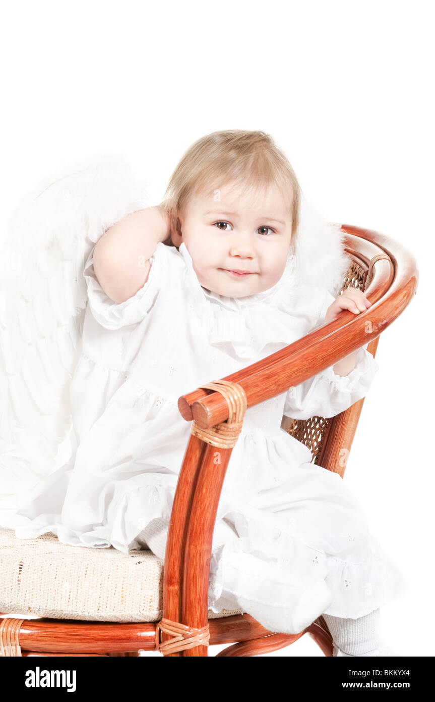 Kind sitzt auf dem Stuhl. Studio gedreht. Isoliert auf weißem Hintergrund. In Engelsflügel Stockfoto