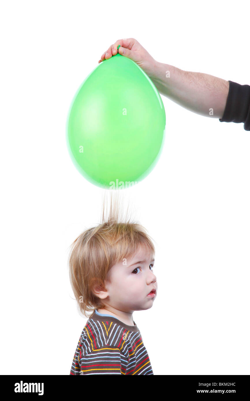kleiner Junge Haar wird von einem Luftballon angezogen mit statischer Elektrizität aufgeladen Stockfoto