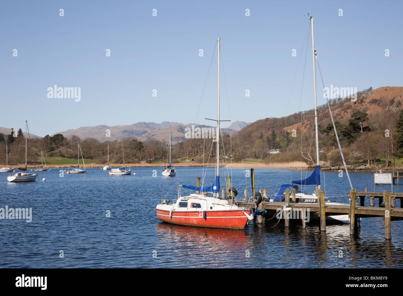 Waterhead, Ambleside, Cumbria, England, UK. Roten Yacht vor Anker von der öffentlichen Anlegestelle auf Windermere im Lake District National Park Stockfoto