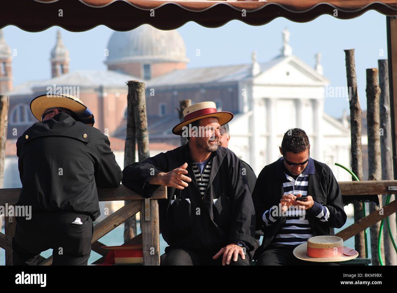 Gondolieri warten auf Touristen in Venedig, Italien. Kirche San Giorgio Maggiore im Hintergrund. Stockfoto