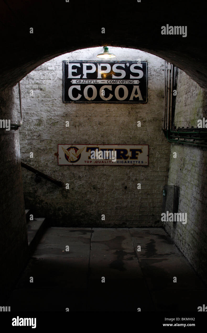 Alte Werbeschilder den unter Bahnsteigtunnel an der Bluebell Railway in Sussex Stockfoto