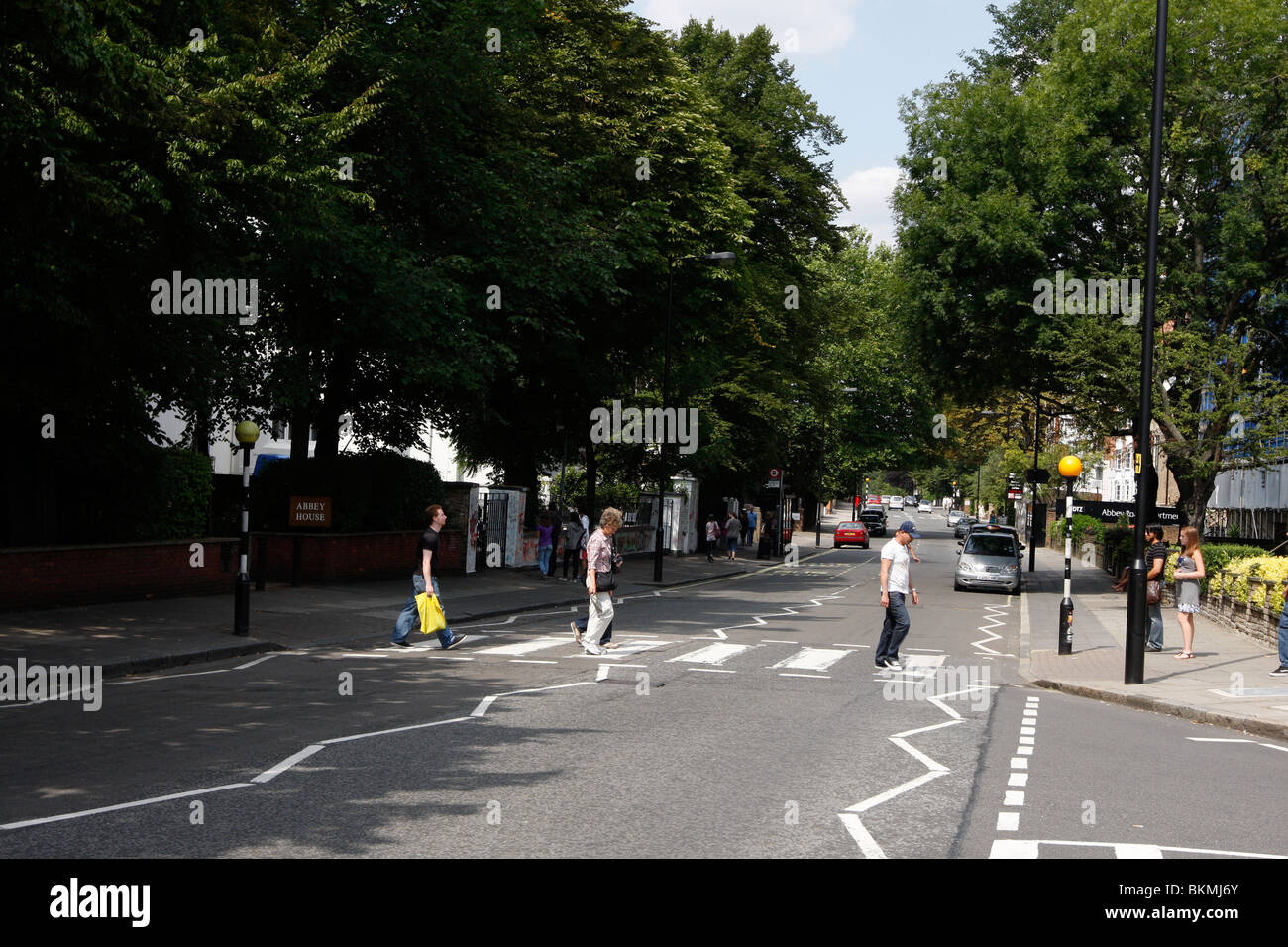 Touristen, die zu Fuß über den berühmten Abbey Road Kreuzung featured auf The Beatles-Album Abbey Road außerhalb des Aufnahmestudios Stockfoto