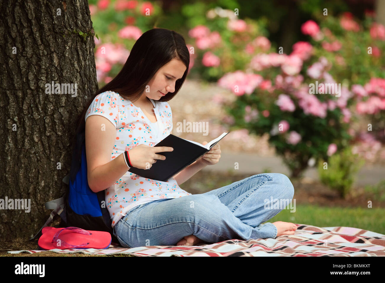Ein junges Mädchen, das Lesen eines Buches im Park Stockfoto