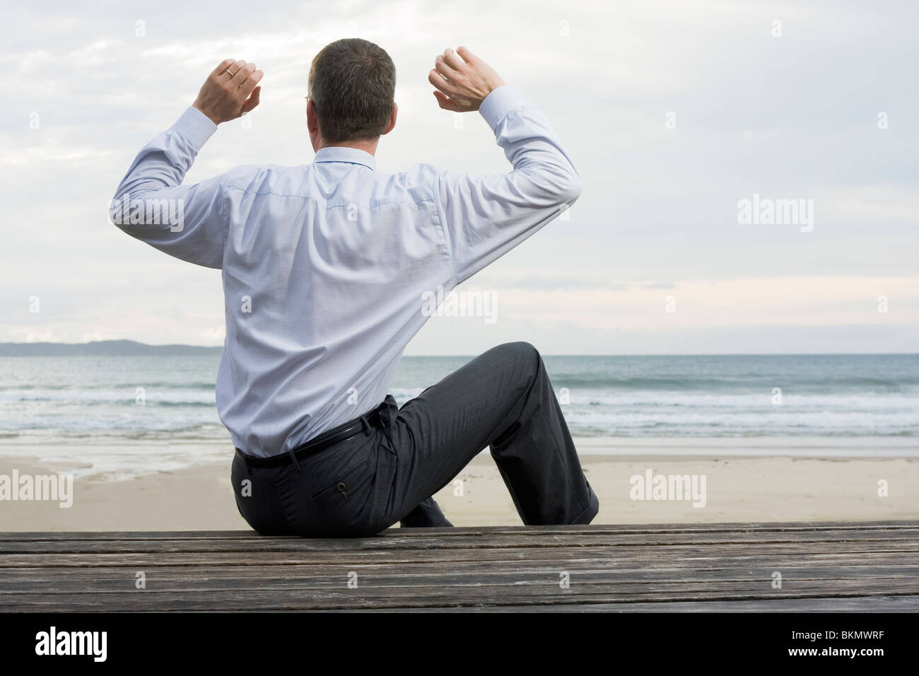 Geschäftsmann Entspannung am Meer sitzend auf einer hölzernen Plattform Stockfoto