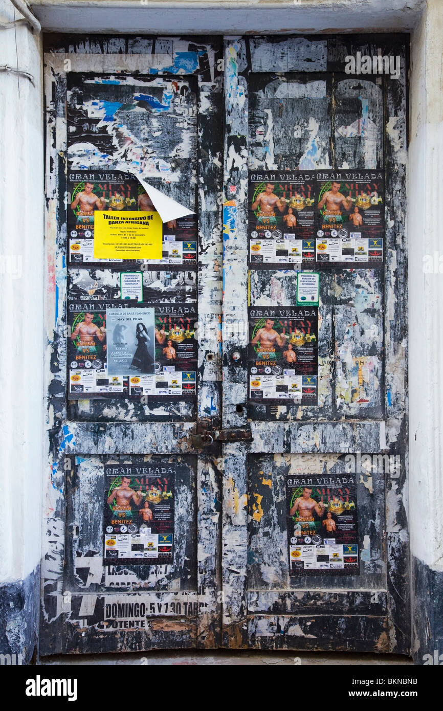 Chiclana, Andalusien, Spanien; Eine alte Tür entlang der Straße bedeckt In der Papier-Werbung Stockfoto