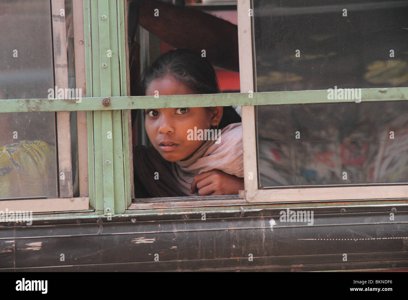 Junges Mädchen schaut aus einem Busfenster in Kalkutta Stockfoto