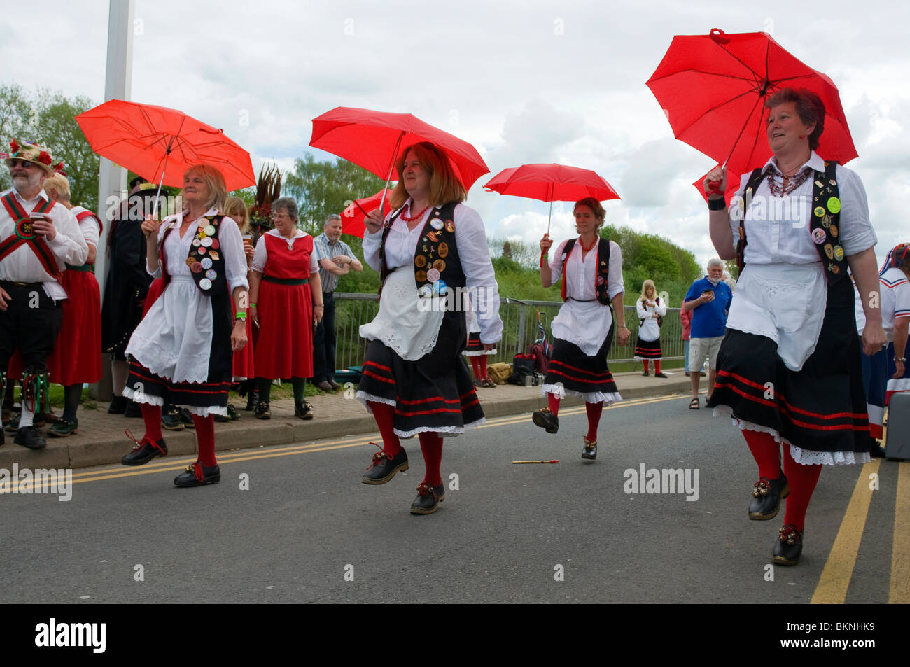 Damen Morris tanzen mit roten Sonnenschirmen auf dem Upton Folk Festival Stockfoto