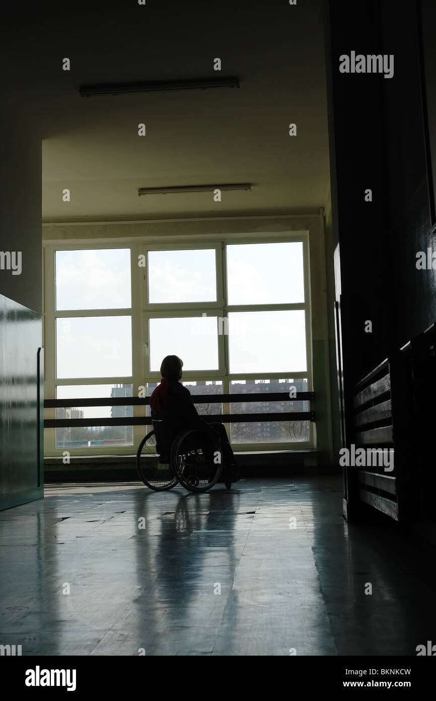 Silhouette der behinderten Frau sitzt im Rollstuhl im Krankenhaus Flur mit Blick auf das Licht, das durch das Fenster Stockfoto