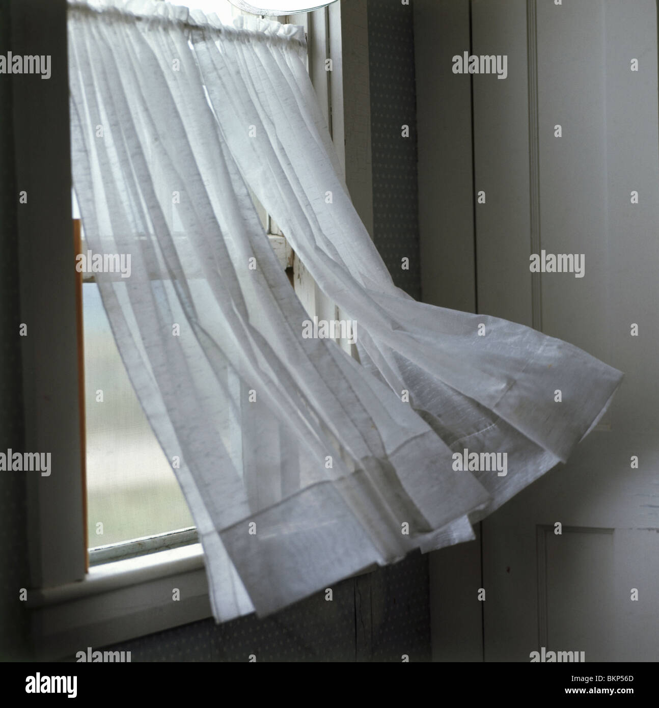 Wind weht einen Vorhang in einem Fenster Stockfoto