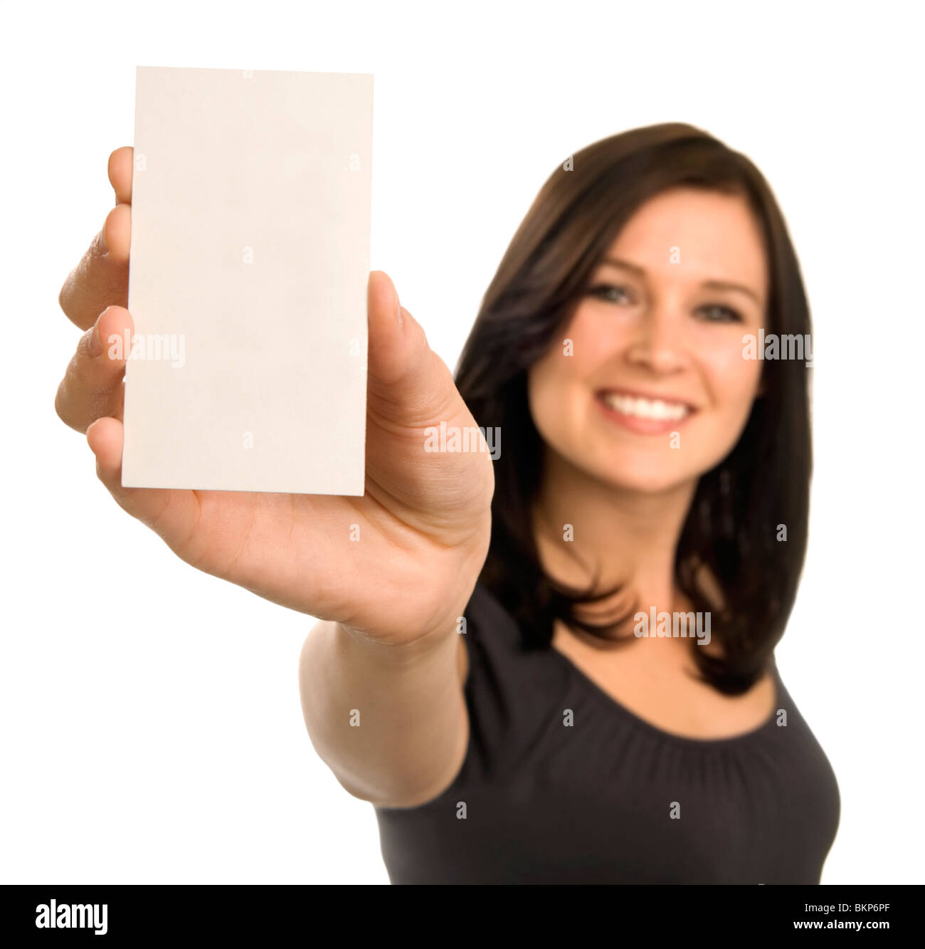 Eine Brünette Frau hält eine vertikale Leere Visitenkarte zu marktüblichen Konditionen. Schwerpunkt liegt auf der Karte mit Gesicht unscharf. Stockfoto