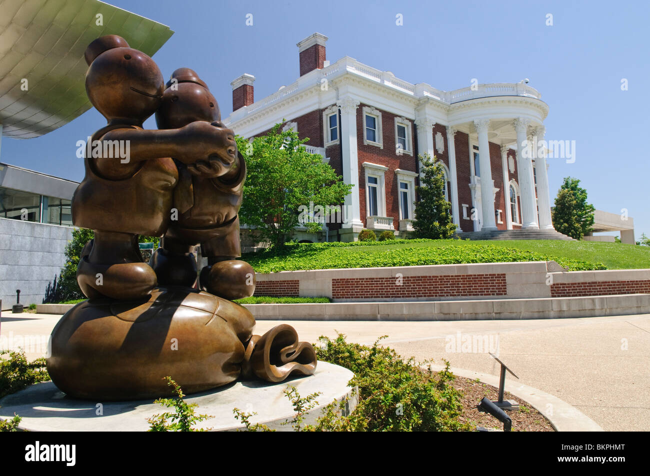 Hunter Museum of American Art Sculptures Chattanooga Tennessee // CHATTANOOGA, Tennessee — Skulpturen auf dem Gelände des Hunter Museum of American Art in Chattanooga, Tennessee. Im Vordergrund steht eine prominente Bronzeskulptur mit zwei umhüllenden Figuren, dahinter die klassische und moderne Architektur des Museums zu sehen. Stockfoto