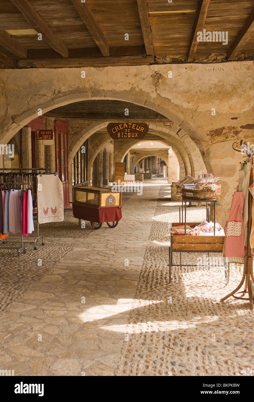 Historische überdachte Stein gewölbten Gehweg mit Geschäften in Market Square von Sauveterre-de-Rouergue Aveyron Midi-Pyrenäen Frankreich Stockfoto