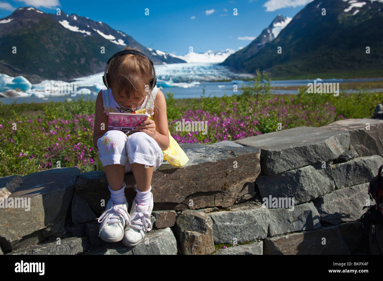 Junges Mädchen spielt ein elektronisches Spiel bei der Forest Service Aussichtsplattform für Spencer-Gletscher in Alaska Yunan Stockfoto