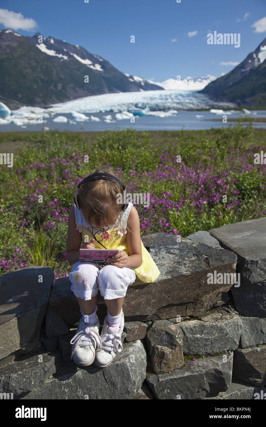 Junges Mädchen spielt ein elektronisches Spiel bei der Forest Service Aussichtsplattform für Spencer-Gletscher in Alaska Yunan Stockfoto