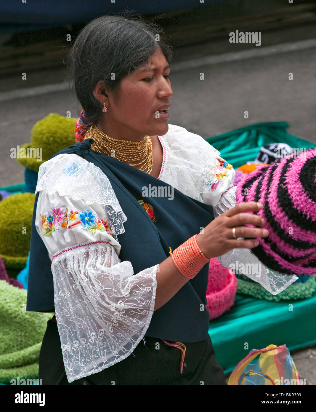 Ecuador, eine indigene ecuadorianischen Frau wollene Mützen in Otavalo Markt zu verkaufen. Stockfoto