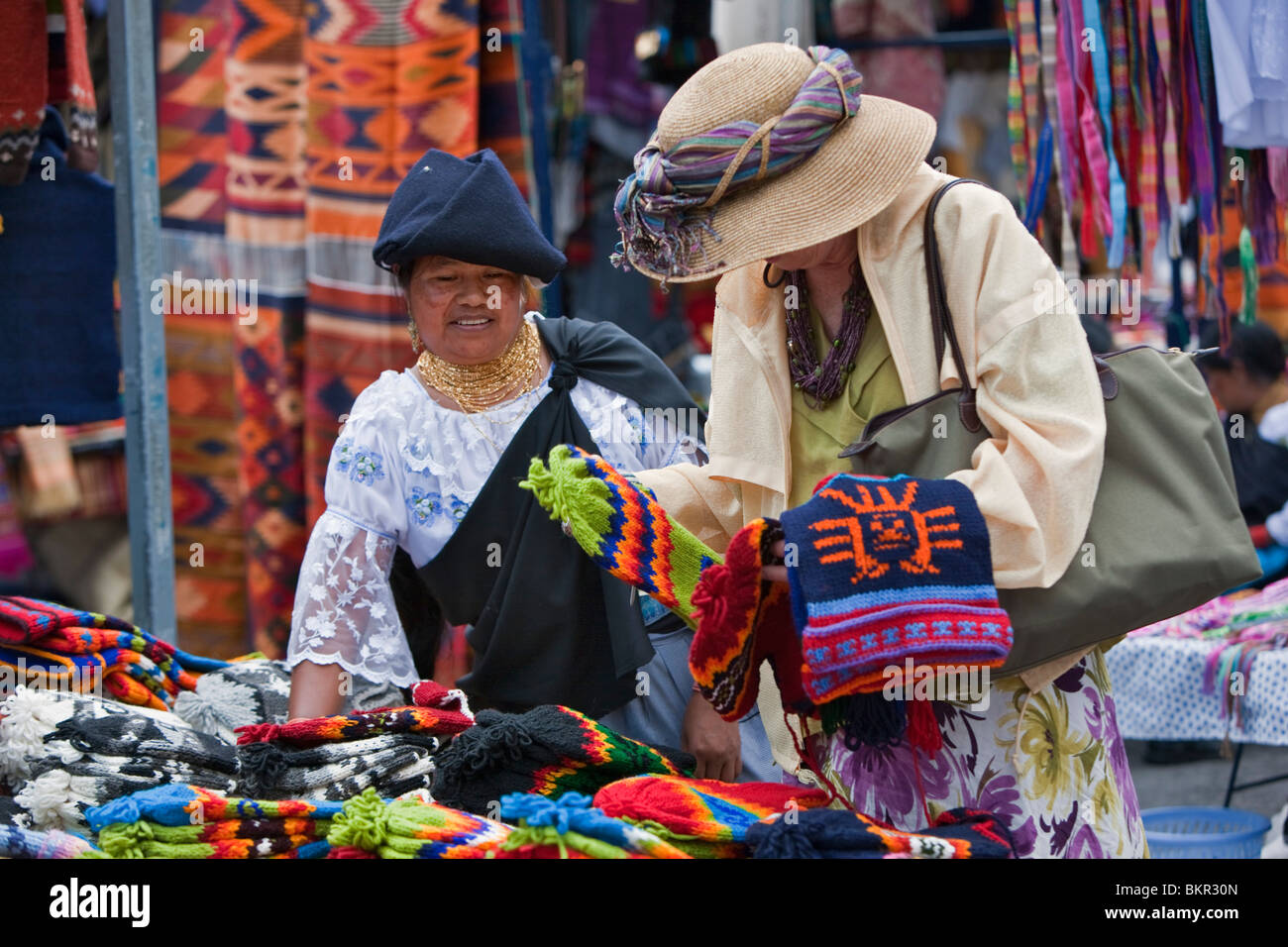 Ecuador, ein Tourist kauft wollene Mützen von eine indigene ecuadorianischen Frau in Otavalo Markt. Stockfoto