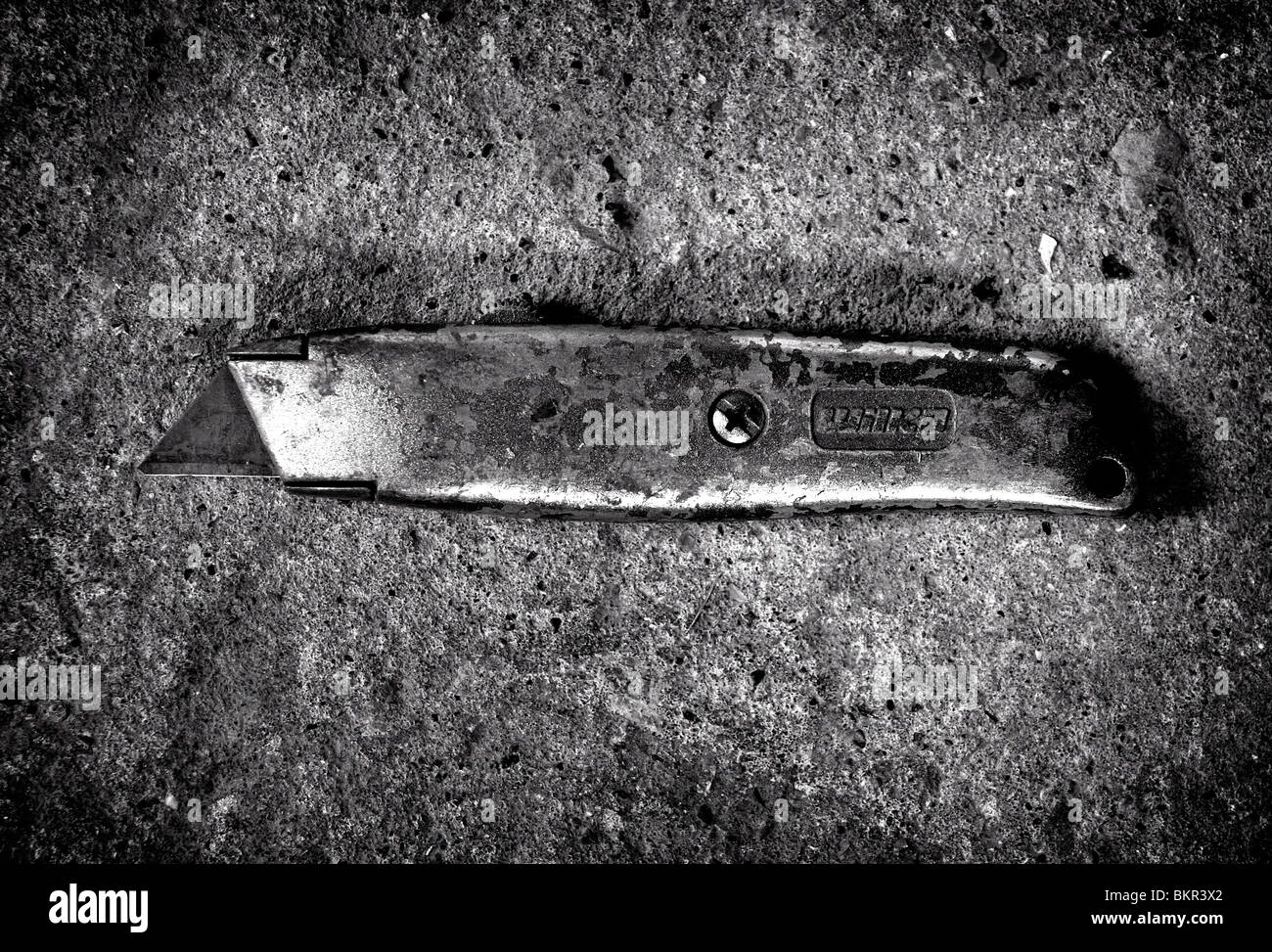 Eine gut genutzte Cuttermesser fotografiert auf einem Betonboden. Stockfoto