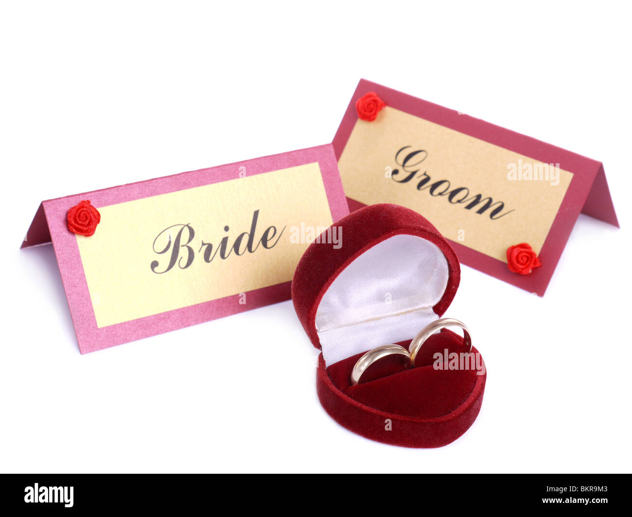 Trauringe in rotem Wildleder-Box und Braut und Bräutigam Namenskarten über weiß Stockfoto