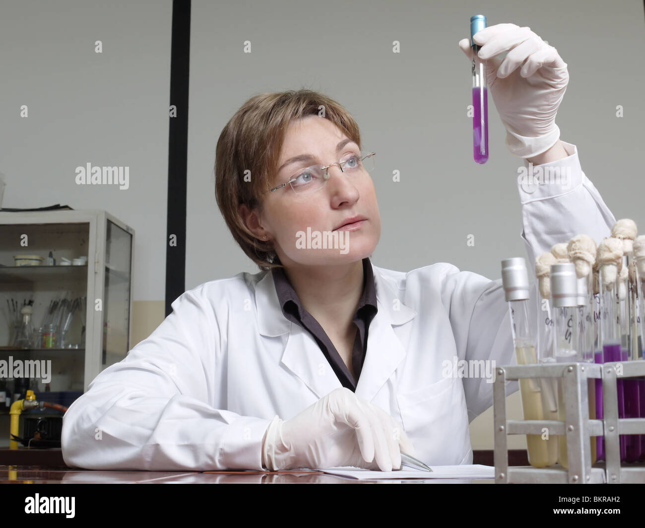 Weibliche Labortechniker betrachten Reagenzglas mit Probe Stockfoto