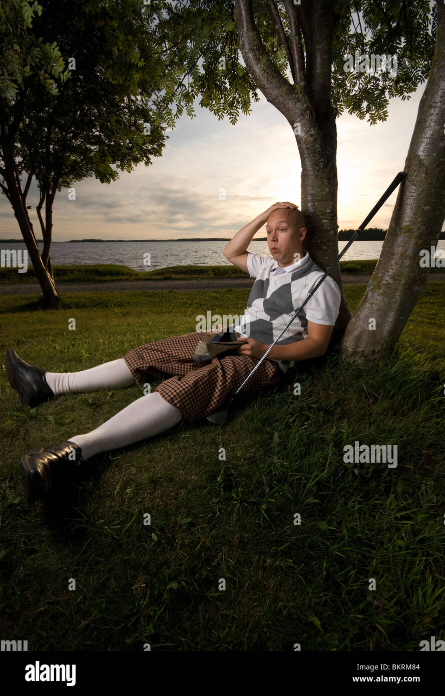 Erschöpft Golfer unter Baum ausruhen. Stockfoto