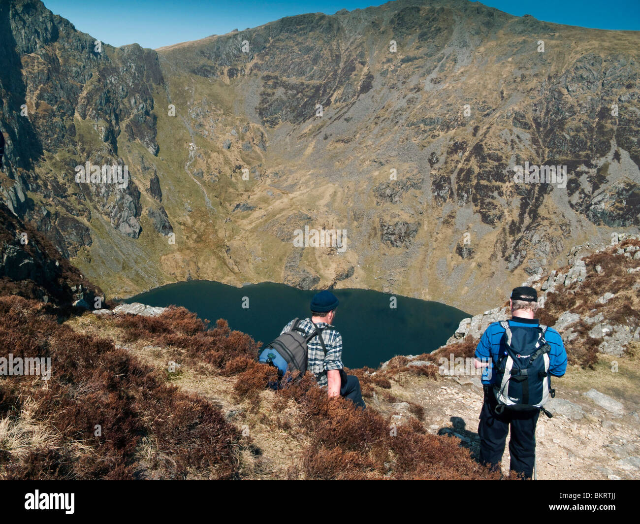 Zwei männliche Rucksacktouristen Blick auf Lake Cau mit den Hängen des Cader Idris steil steigt im Hintergrund ruht Stockfoto
