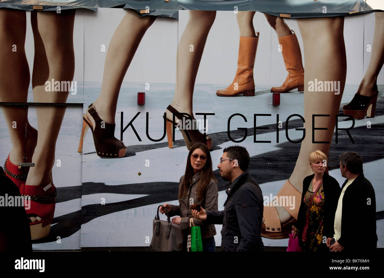 Menschen übergeben eine große Mode-Plakat für Kurt Geiger. Covent Garden im West End von London. Stockfoto