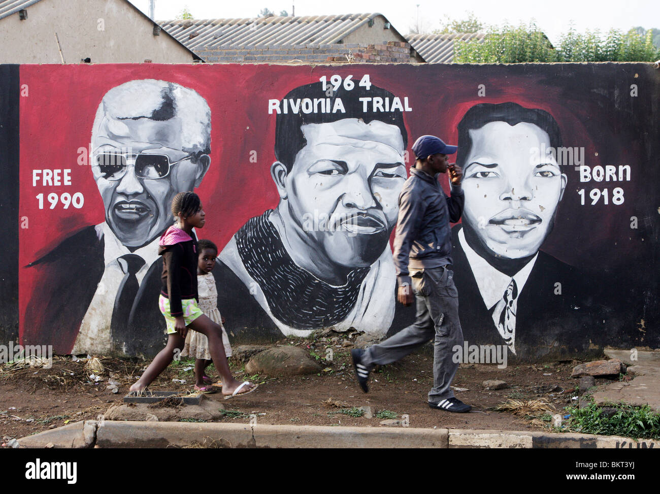Kinder, vorbei an einem Wandbild Nelson Mandela im Township Soweto, Johannesburg, Südafrika Stockfoto