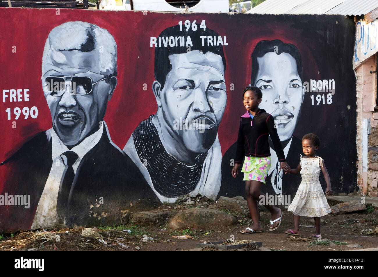 Kinder, vorbei an einem Wandbild Nelson Mandela im Township Soweto, Johannesburg, Südafrika Stockfoto
