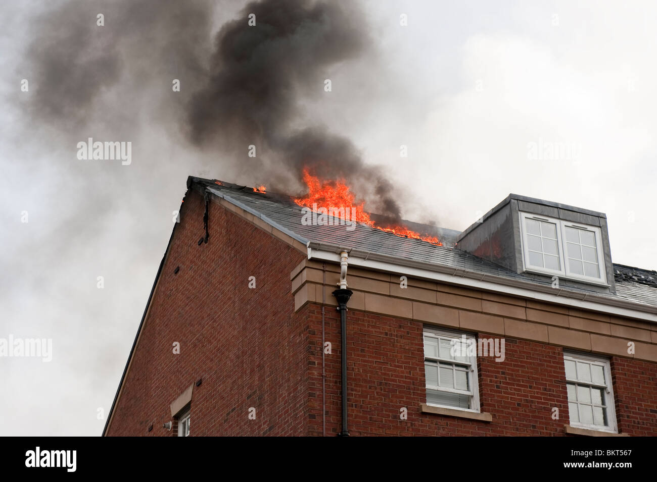 Haus Feuer Flammen aus Dach brütete Stockfoto