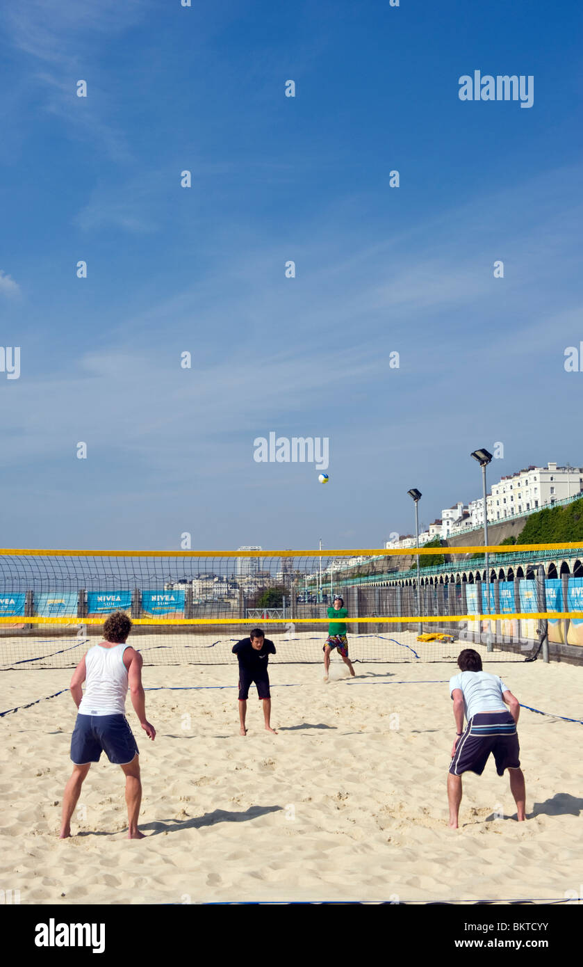Menschen spielen Beach-Volleyball auf Sand am Meer auf Brighton Seafront in warmem Wetter und blauem Himmel Stockfoto
