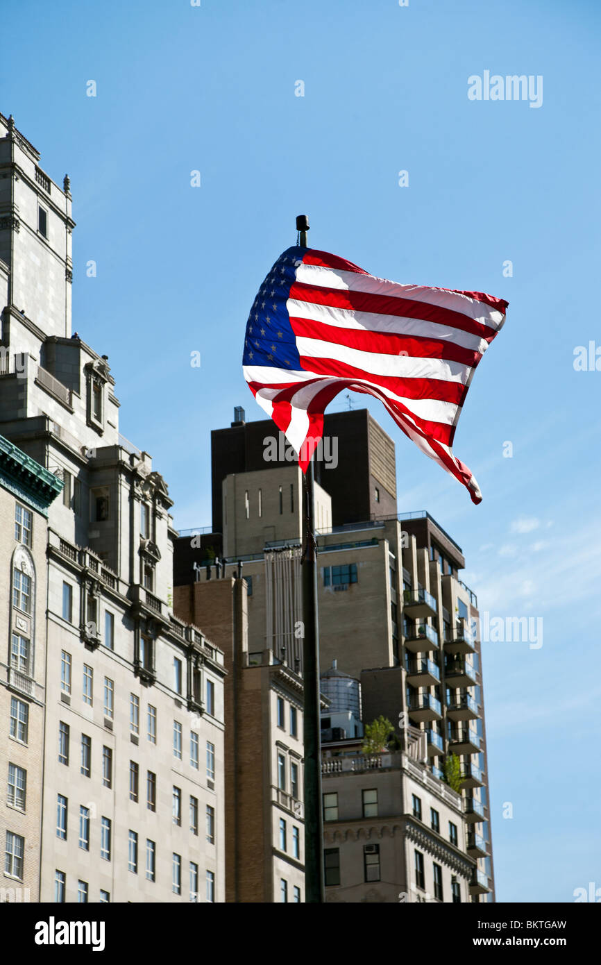 Amerikanische Flagge fliegt unbeschwert in eine steife Brise vor Hintergrund des blauen Himmels & teure oberen Fifth Avenue Immobilien Manhattan Stockfoto