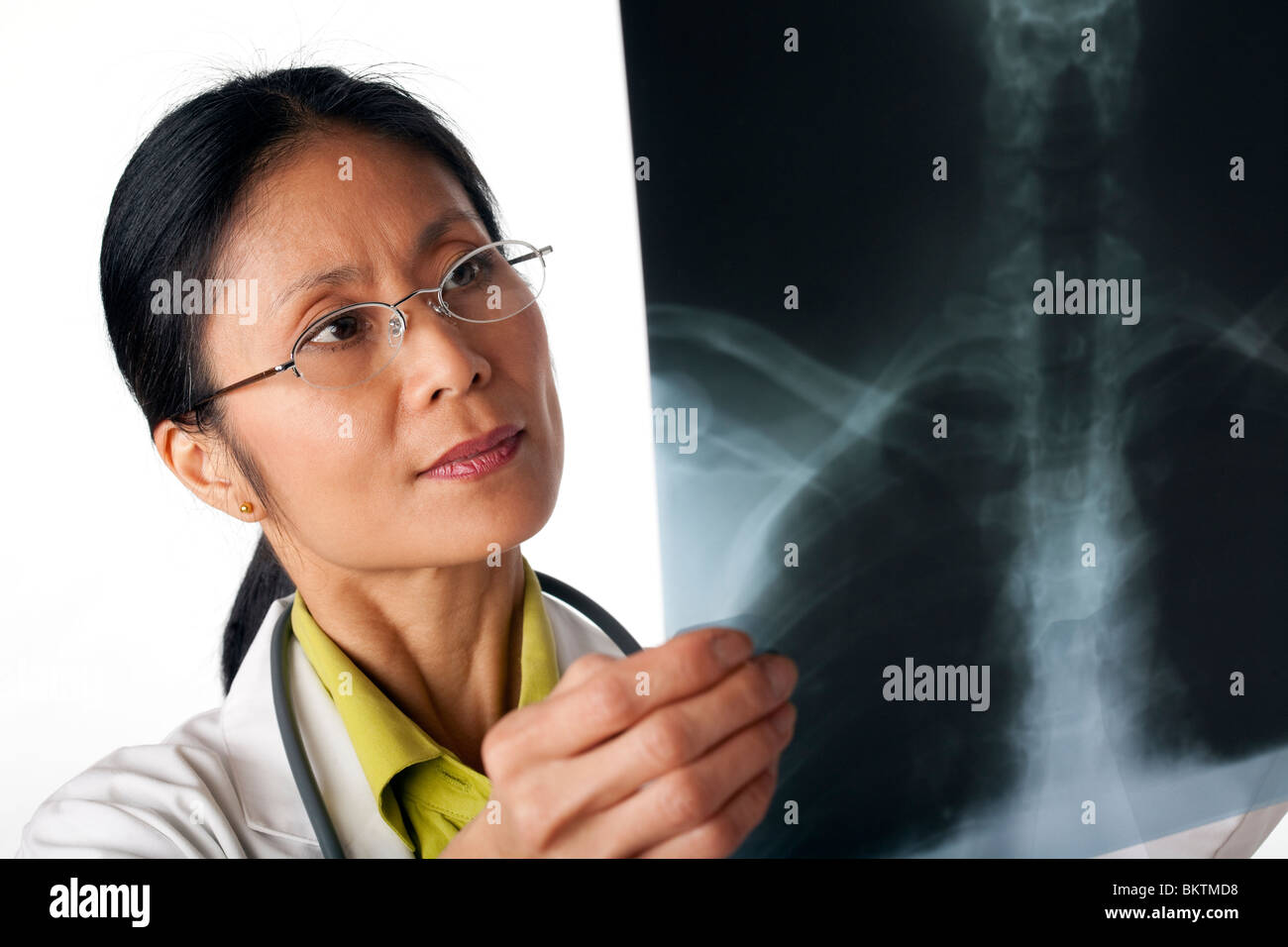 Asiatische Ärztin Blick auf eine Röntgenaufnahme der Lunge. Horizontalen Schuss. Isoliert auf weiss. Stockfoto