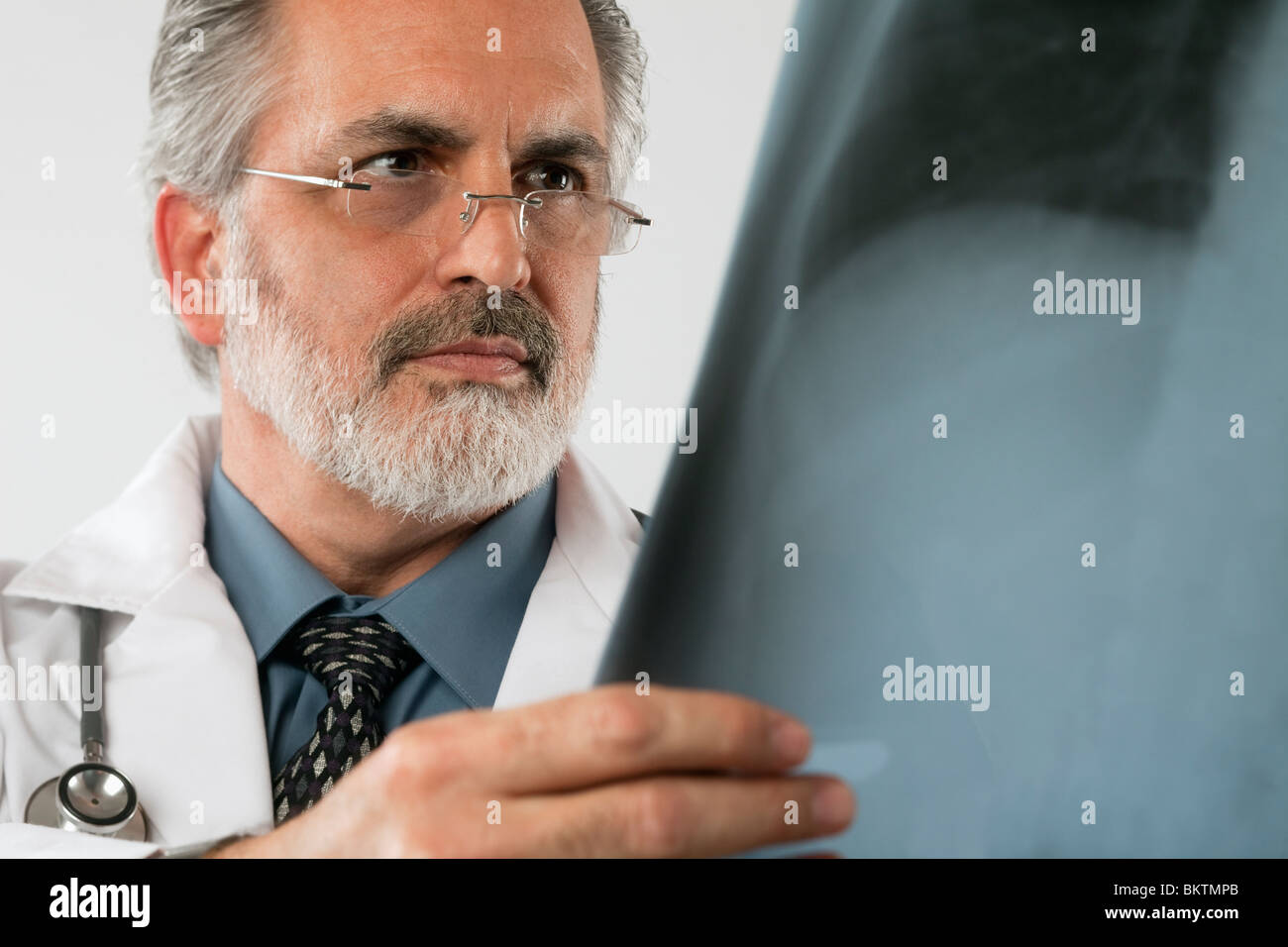 Beschnitten, close-up Portrait eines Arztes tragen Brillen und einen weißen Laborkittel und eine Röntgenaufnahme aufmerksam betrachten. Horizontalen Schuss. Stockfoto