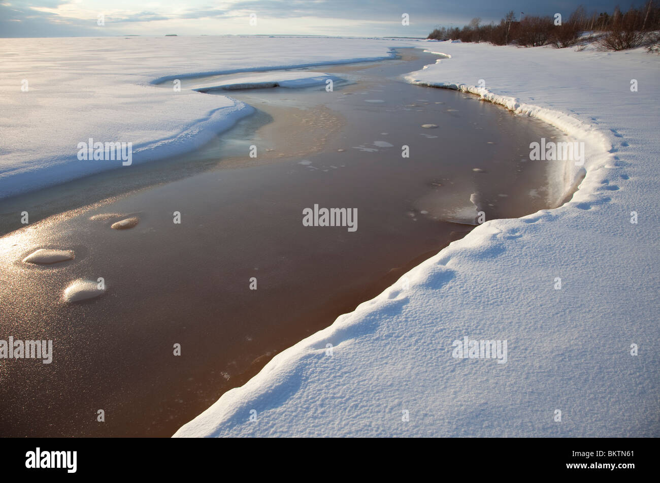 Riss auf schmelzendem Meereis gefüllt mit bräunlichem Wasser, Finnland Stockfoto