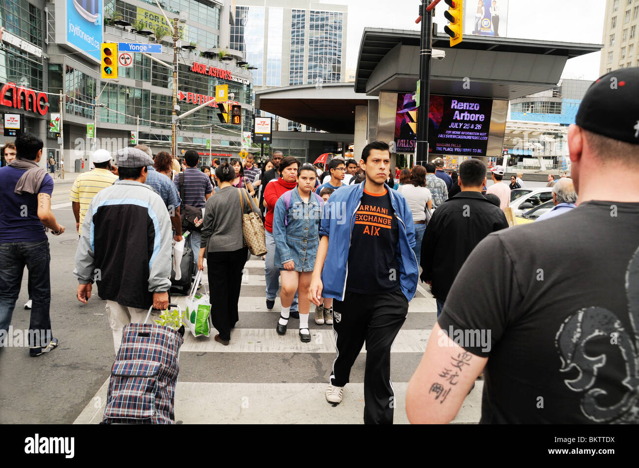 Eine Gruppe von Fußgängern überqueren die Straße an einer Kreuzung an der Ecke der Yonge und Dundas Straßen, in der Innenstadt von Toronto, Ontario, Kanada. Stockfoto