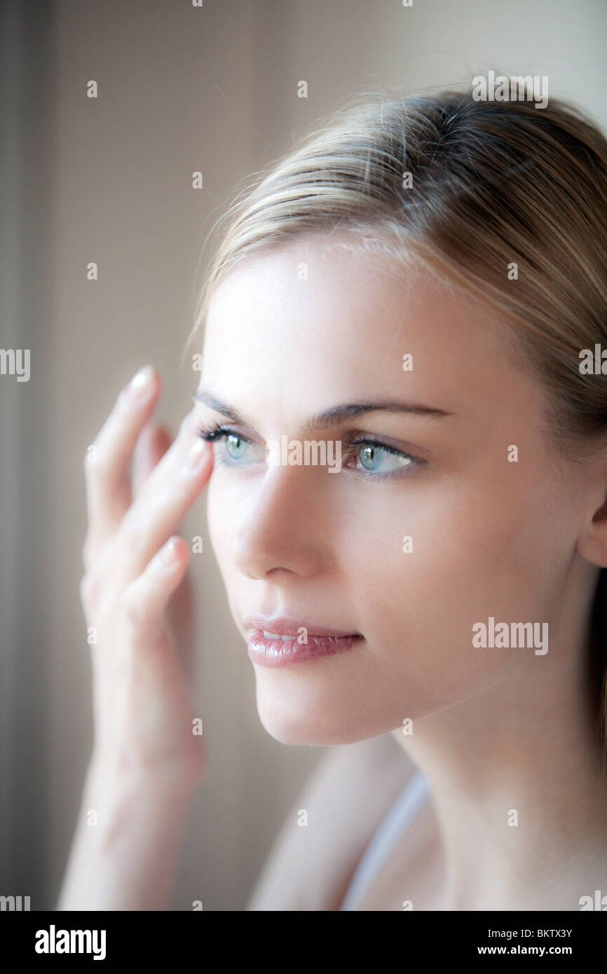 Frau gilt Gesichtscreme Stockfoto