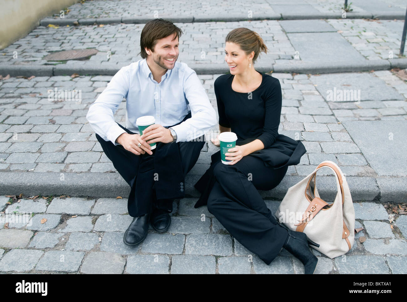 Mann und Frau sitzen auf Treppe, Kaffee trinken Stockfoto